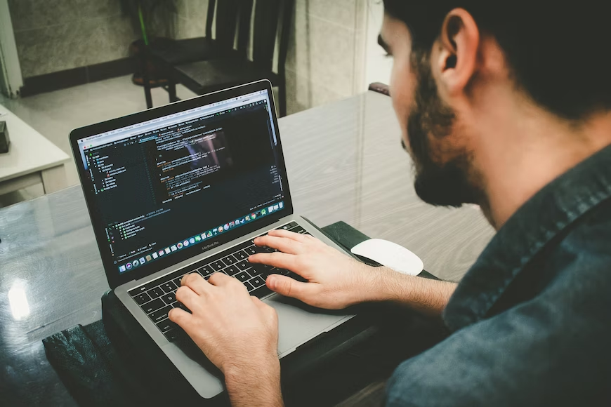 A gentleman diligently operates a laptop computer, focusing on his work.png